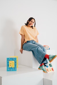 a woman sitting on top of a set of cubes with books